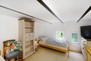 a bedroom with a bed and a tv and a chair at Tiny Appartment Xanten am See in Xanten