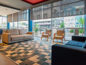 a lobby with couches and chairs in a building at ibis budget Porto Alegre - Super Econômico in Porto Alegre