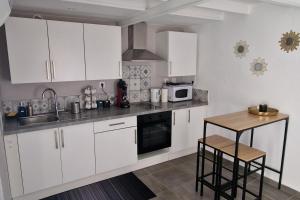 a kitchen with white cabinets and a sink and a table at Marguerite - Charme et confort in Orange