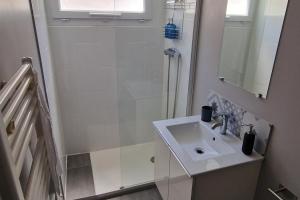 a white bathroom with a sink and a shower at Marguerite - Charme et confort in Orange