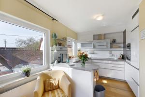 a kitchen with white cabinets and a large window at Fewo-Taunus-Panoramablick in Königstein im Taunus