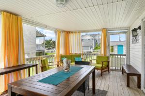 a screened porch with a wooden table and chairs at Bertie Street Cottage in Chincoteague