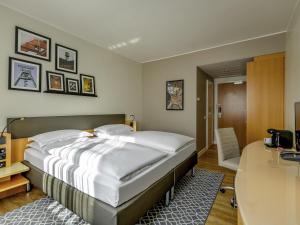 a bedroom with a large bed and a desk at Mercure Hotel Bochum City in Bochum