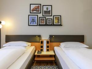 two beds in a room with pictures on the wall at Mercure Hotel Bochum City in Bochum +129 photos