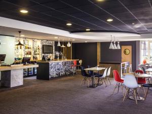 a restaurant with tables and chairs and a bar at ibis London Barking in Barking