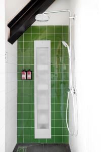 a green tiled bathroom with a shower with a mirror at Lennepserf - De Hoeven in Veessen
