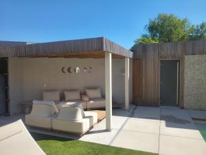 eine Terrasse mit Sofa und Stühlen unter einem Pavillon in der Unterkunft Nova Nocte Urban Private Pool & Spa Retreat in Tongeren
