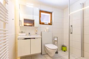 a white bathroom with a toilet and a sink at Hauswurz in Thun