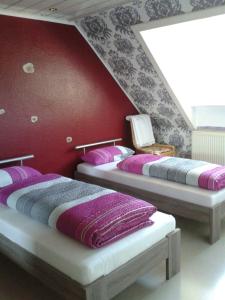 2 Betten in einem Zimmer mit roter Wand in der Unterkunft Messezimmer Hannover Langenhagen - room agency in Hannover