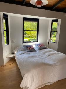 a bedroom with a large bed with two windows at Veddinge Odsherreddenmark - House With Seaview in Asnæs
