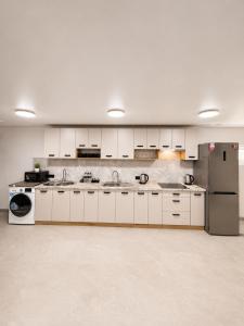 a large kitchen with white cabinets and a refrigerator at EVURI Rooms in Uzhhorod +16 photos