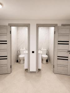 a bathroom with two toilets and two doors at EVURI Rooms in Uzhhorod