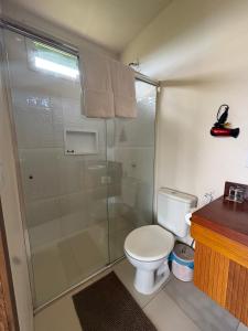 a bathroom with a toilet and a glass shower at Pousada Mão de Deus in Vila Tepequém +23 photos