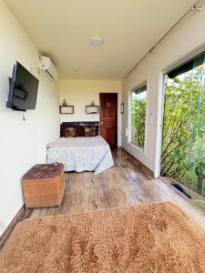 a bedroom with a bed and a flat screen tv at Pousada Mão de Deus in Vila Tepequém