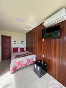 a bedroom with a bed and a flat screen tv at Pousada Mão de Deus in Vila Tepequém