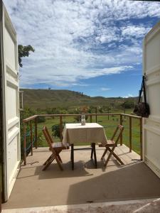 a table and chairs on a balcony with a view at Pousada Mão de Deus in Vila Tepequém