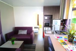 a living room with a purple couch and a kitchen at Lodges camp in Setúbal