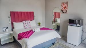 a bedroom with a large white bed with a pink headboard at Divine Guest Lodge in Rustenburg +21 photos