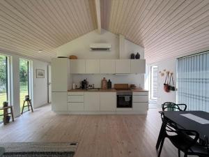 a kitchen with white cabinets and a table with chairs at Modern And Stylish Summer Cabin in Vejby