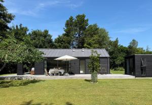 a black cabin with a table and an umbrella at Modern And Stylish Summer Cabin in Vejby