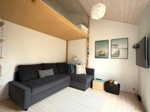 a living room with a couch and a tv at Modern And Stylish Summer Cabin in Vejby