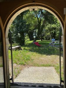 an open door to a park with people sitting in the grass at Le Moulin de Tiquetorte in Moulis-en-Médoc