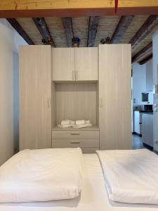 a bedroom with two beds and cabinets and a kitchen at Cozy tiny flat in Cadore Dolomiti in Calalzo