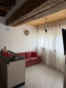 a living room with a red couch and white curtains at Cozy tiny flat in Cadore Dolomiti in Calalzo