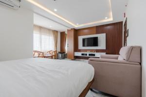 a bedroom with a bed and a couch and a tv at Hotel Rasballa Grand in Bhadrāchalam Road