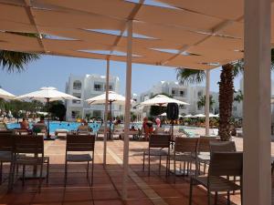 ein Pool mit Tischen, Stühlen und Sonnenschirmen in der Unterkunft Riad Meninx in Bin Rhilouf + 12 Fotos