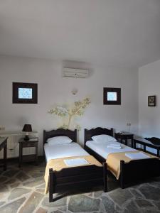 two beds in a room with two tables and two windows at Amalthia hotel in Límni