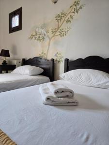 two beds with white sheets and towels on them at Amalthia hotel in Límni +37 photos