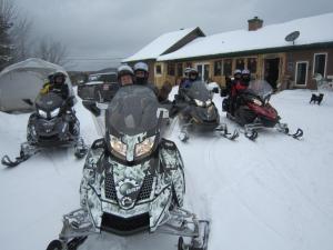 un grupo de personas de pie en la nieve en motos de nieve en Le Gîte Ambrelane, en Thetford Mines