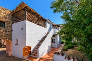 a white house with a staircase on the side of it at Sea View Within Walking Distance of the Beach in Baja Sardinia
