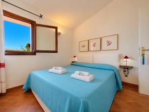 a bedroom with a blue bed with towels on it at Sea View Within Walking Distance of the Beach in Baja Sardinia