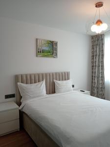 a bedroom with a large bed with white sheets at Zen aeroport confort in Sînnicoară