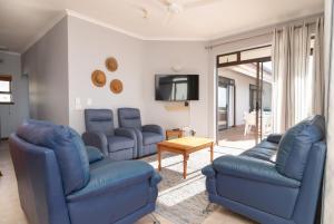 a living room with blue chairs and a tv at Chaka Terraces 10 in Ballito