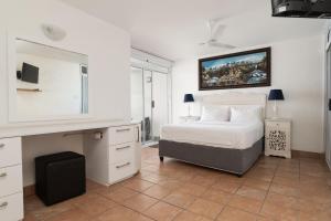 a white bedroom with a bed and a tv at Chakas Cove 34 in Ballito