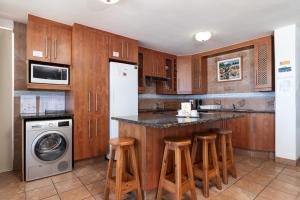 a kitchen with wooden cabinets and a island with bar stools at Chakas Cove 34 in Ballito