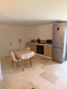 a kitchen with a table and a stainless steel refrigerator at Studio avec terrasse et parking privé in Château-Arnoux-Saint-Auban