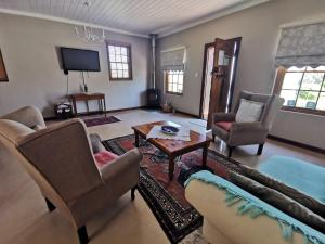 a living room with a couch and chairs and a table at Somerset Grace Cottage in Somerset West