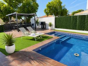 a swimming pool in a backyard with two chairs and a table at Lux Villa with Year-Round Heated Pool & Game Room in Montequinto