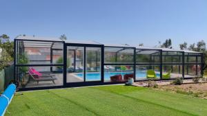 a large glass house with a pool in it at Poço e Meio - Padel & Pool in Santiago da Guarda