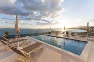 a swimming pool with lounge chairs and a view of the ocean at Stella Maris Deluxe in Podstrana