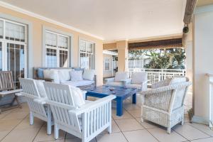 a porch with white chairs and a blue table at Colwyn Drive 53 in Sheffield Beach