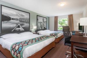 a hotel room with two beds and a desk at Super 8 by Wyndham Peterborough in Peterborough