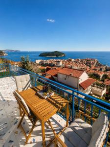 a balcony with a wooden table and chairs and the ocean at Apartment Iris in Dubrovnik