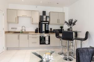 a kitchen with white cabinets and a glass table at Bradford Chic City-Centre Apartment in Bradford