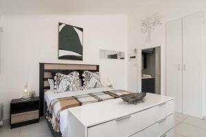 a white bedroom with a large bed with a dresser at La Mer 14 in Ballito