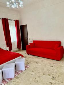 a red couch in a living room with red curtains at Sicilia Benessere in Montedoro
